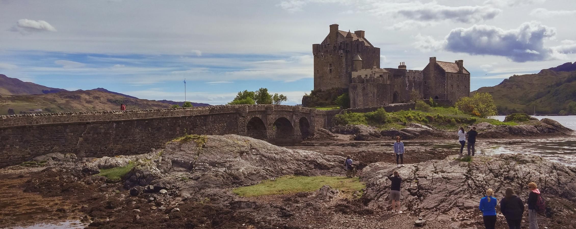 People walk at the foot of a large castle.