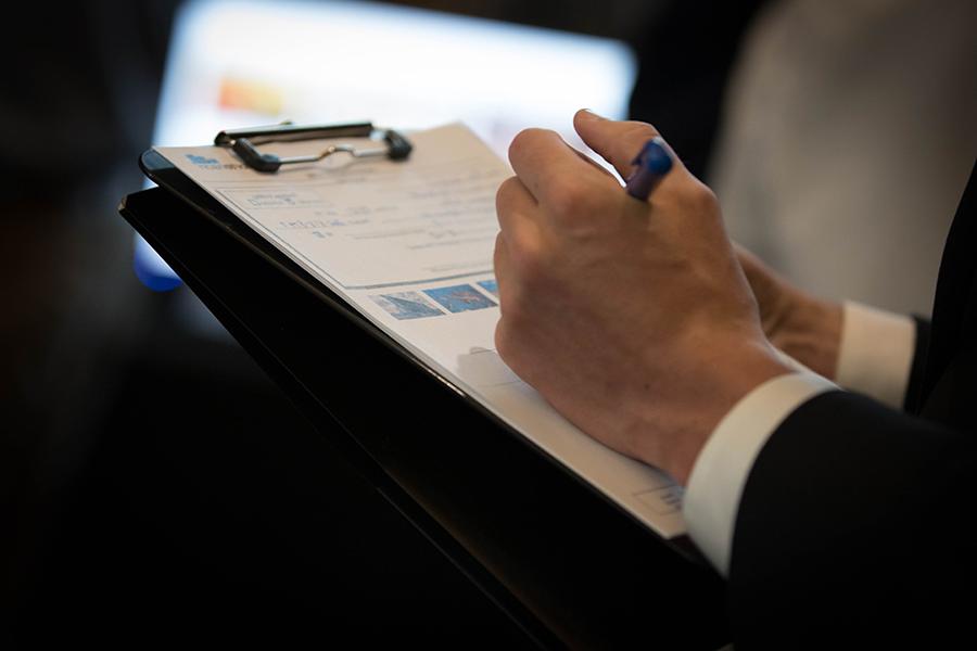 A close up photo of a hand writing on a clipboard.